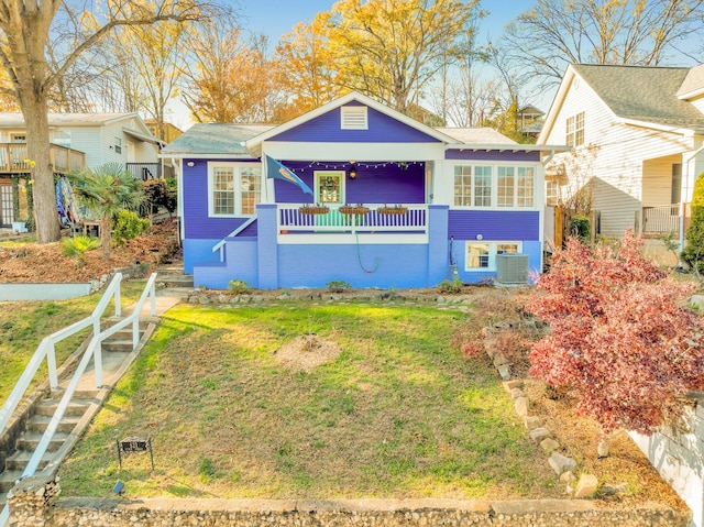 view of front of house with a front lawn, cooling unit, and a porch