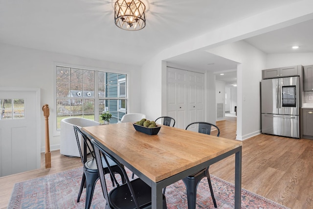 dining space featuring a chandelier, light hardwood / wood-style floors, and lofted ceiling