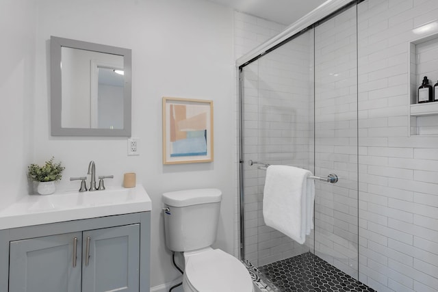 bathroom featuring vanity, toilet, and a shower with door