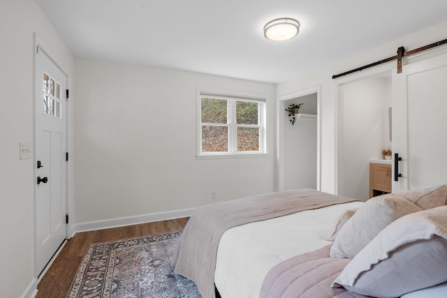 bedroom featuring a barn door and dark hardwood / wood-style flooring