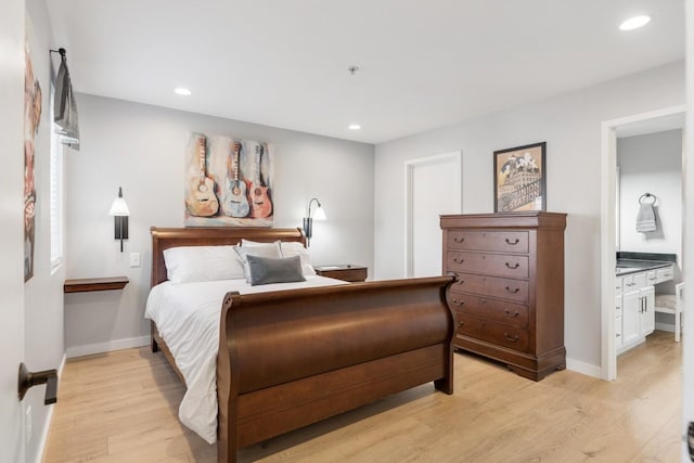 bedroom with ensuite bathroom and light hardwood / wood-style flooring