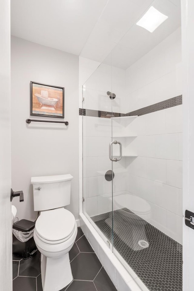 bathroom featuring toilet, tile patterned floors, and a shower with door