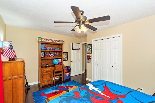 bedroom with ceiling fan, dark hardwood / wood-style floors, a textured ceiling, and a closet