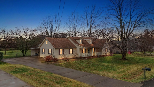 new england style home with a carport, covered porch, and a yard