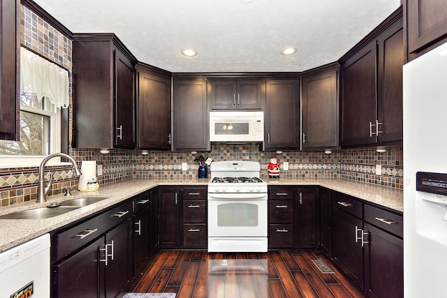 kitchen with dark hardwood / wood-style flooring, white appliances, sink, and tasteful backsplash