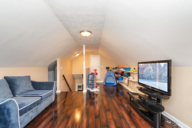 recreation room with a textured ceiling, dark wood-type flooring, and vaulted ceiling