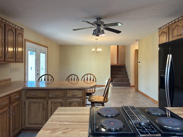 kitchen with carpet flooring, kitchen peninsula, a textured ceiling, black appliances, and ceiling fan with notable chandelier