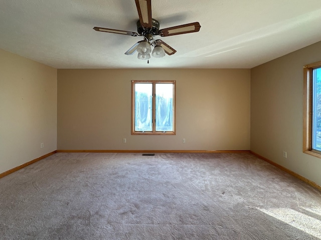 empty room with ceiling fan, light colored carpet, and a textured ceiling