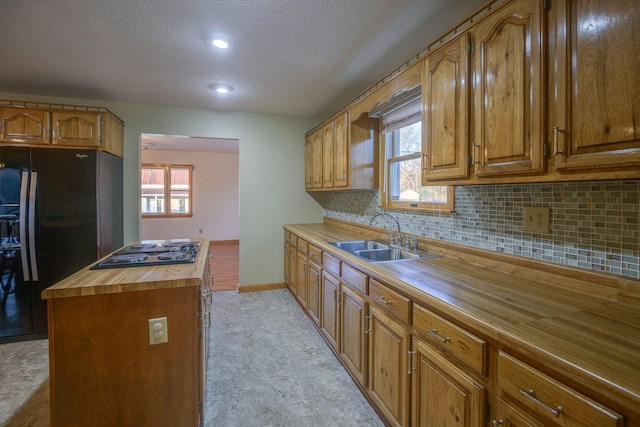 kitchen with backsplash, wooden counters, black appliances, sink, and a textured ceiling