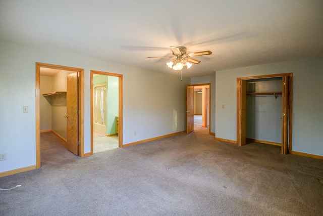 unfurnished bedroom with a spacious closet, ceiling fan, carpet floors, and connected bathroom