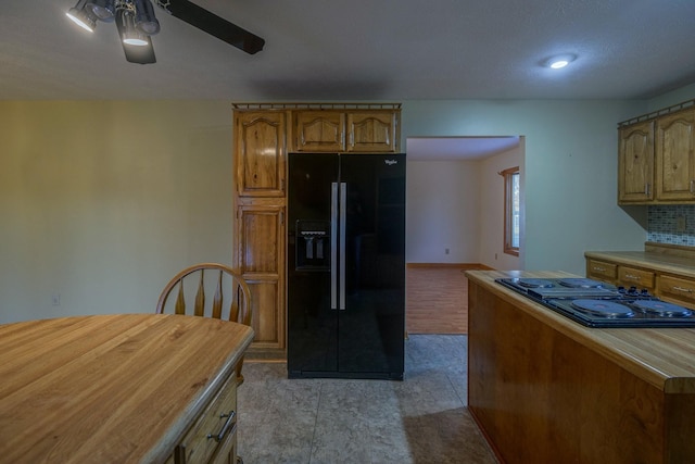 kitchen with ceiling fan, gas stovetop, backsplash, black fridge with ice dispenser, and light tile patterned floors