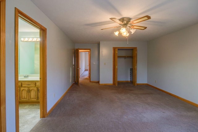 unfurnished bedroom with carpet flooring, a walk in closet, ceiling fan, connected bathroom, and a closet