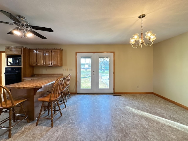 dining room with a textured ceiling, french doors, and ceiling fan with notable chandelier