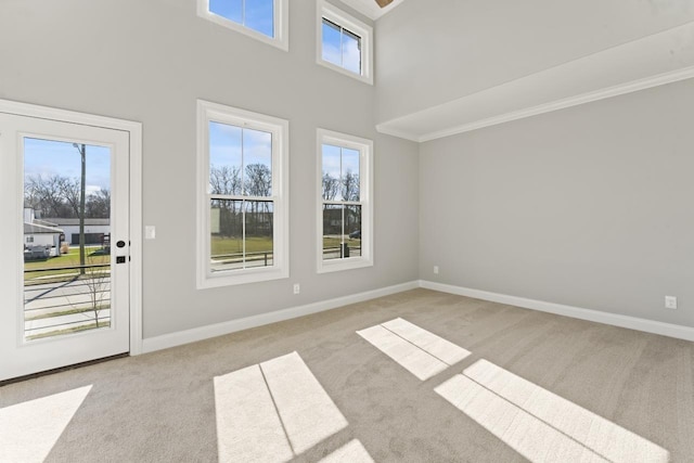 empty room with a high ceiling, light colored carpet, and a wealth of natural light