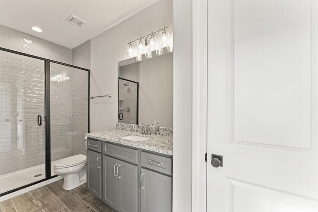 bathroom with vanity, a shower with shower door, and toilet