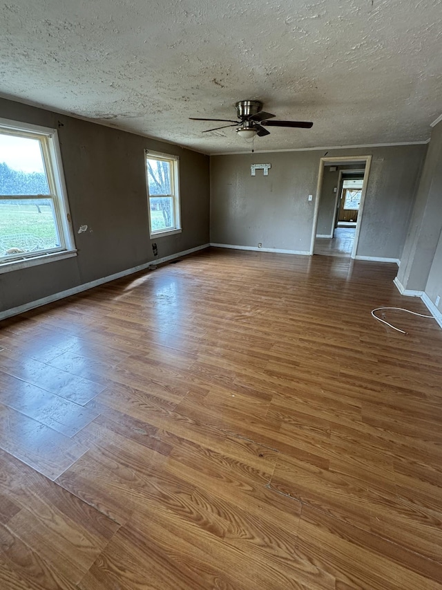 empty room with ceiling fan, wood-type flooring, and a textured ceiling