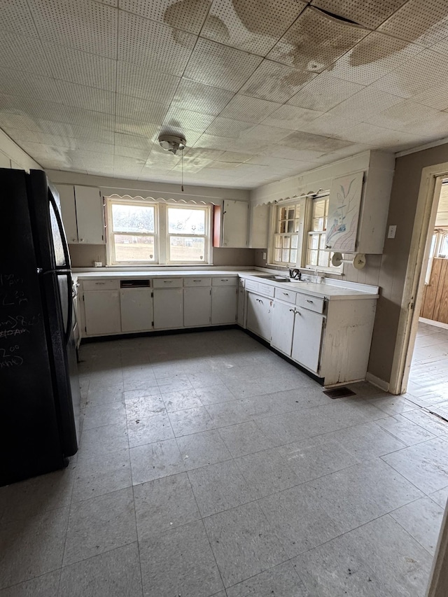 kitchen with white cabinets, black fridge, and sink