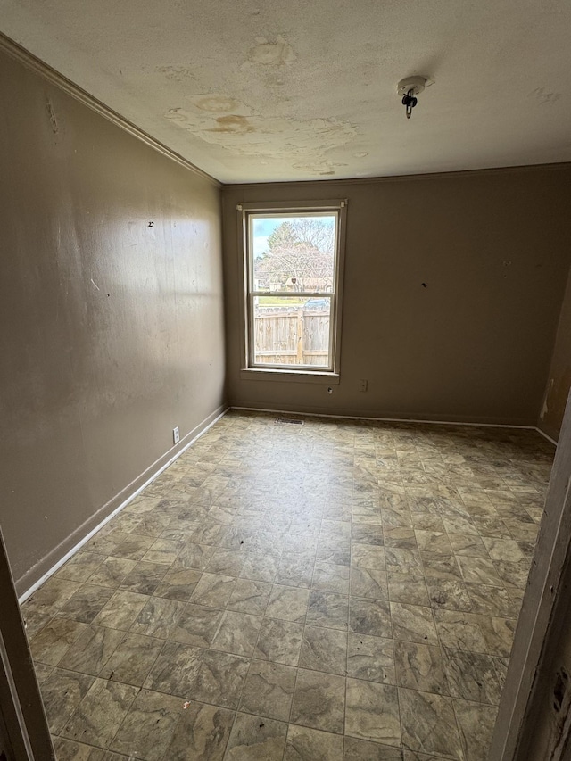 empty room featuring crown molding and a textured ceiling