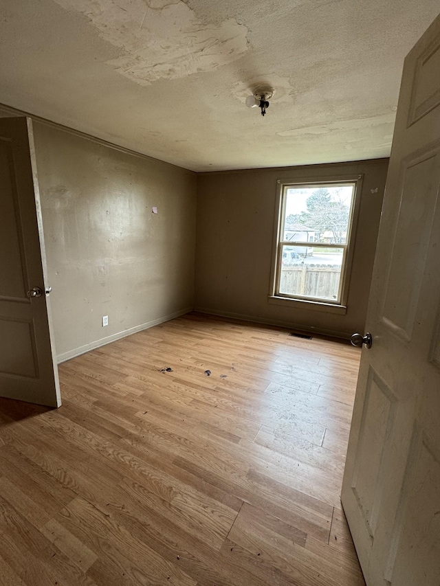 empty room with a textured ceiling and light wood-type flooring