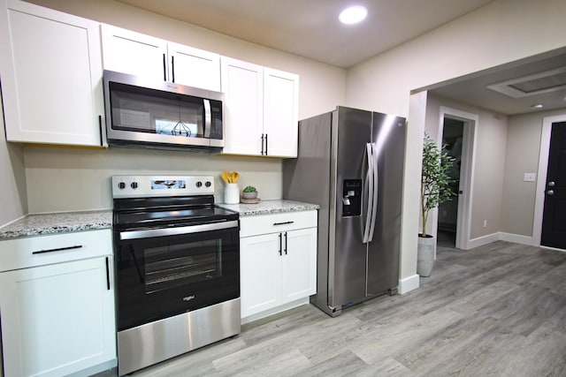 kitchen with appliances with stainless steel finishes, light hardwood / wood-style floors, and white cabinetry