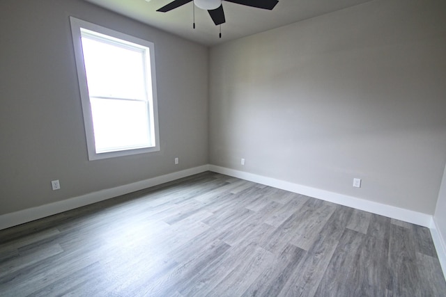 spare room with light wood-type flooring, ceiling fan, and a healthy amount of sunlight