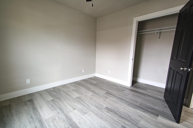 unfurnished bedroom with light wood-type flooring and a closet