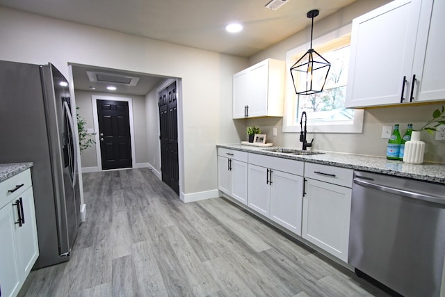 kitchen with white cabinetry, sink, stainless steel appliances, pendant lighting, and light wood-type flooring