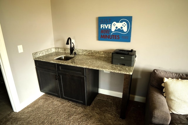 bar with dark colored carpet, light stone countertops, and sink