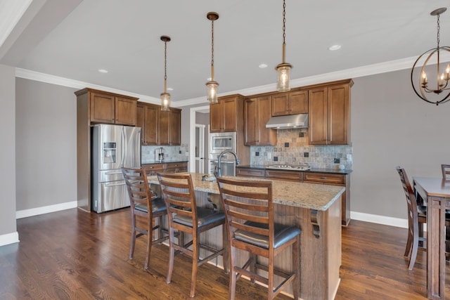 kitchen featuring stainless steel appliances, backsplash, dark wood-type flooring, and under cabinet range hood