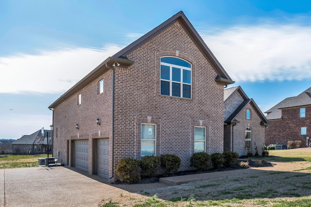 view of front of house featuring a garage, driveway, brick siding, and central AC