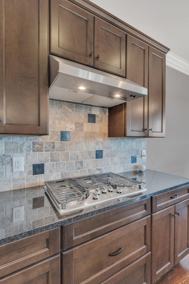 kitchen with dark stone counters, stainless steel gas stovetop, decorative backsplash, and under cabinet range hood