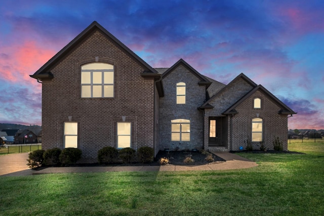 view of front of house with brick siding and a lawn