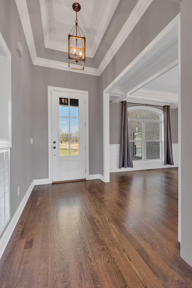 entryway with a chandelier, wood finished floors, baseboards, ornamental molding, and a raised ceiling