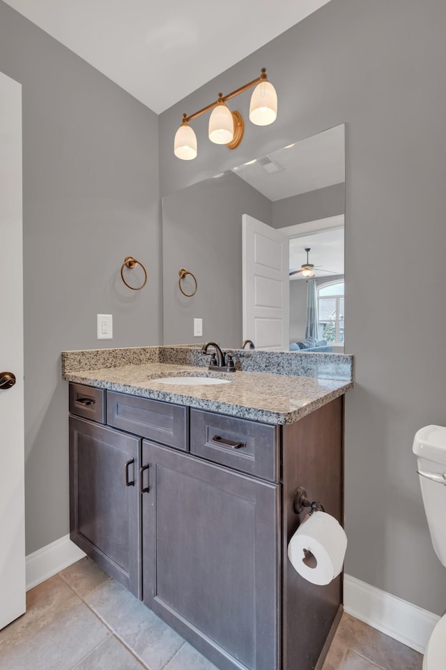 half bathroom featuring toilet, tile patterned flooring, baseboards, and vanity