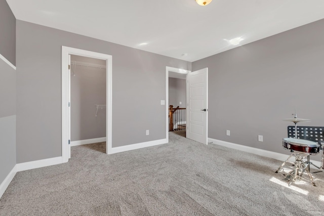 unfurnished bedroom featuring carpet floors, a spacious closet, and baseboards