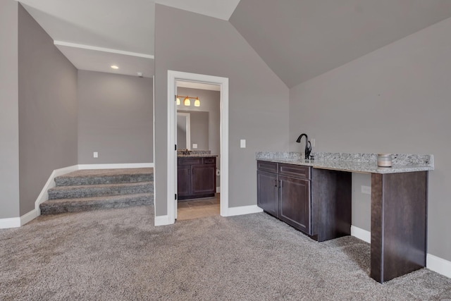 bar with lofted ceiling, baseboards, a sink, and light colored carpet