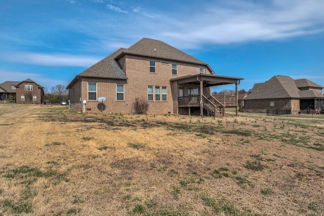 back of house featuring brick siding, a shingled roof, stairs, a lawn, and a wooden deck