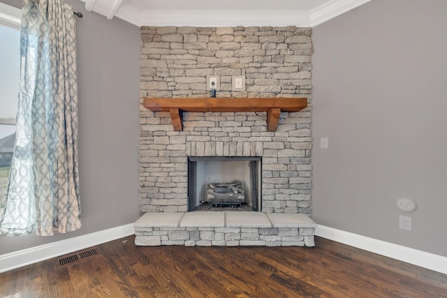 room details with visible vents, a fireplace with raised hearth, wood finished floors, and ornamental molding