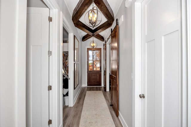 entryway featuring beamed ceiling, light hardwood / wood-style floors, and a chandelier