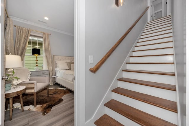 staircase featuring wood-type flooring and crown molding