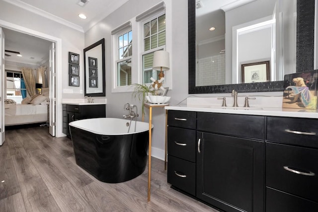 bathroom with a bathing tub, wood-type flooring, vanity, and crown molding