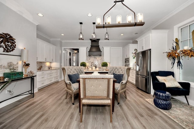 dining space with a notable chandelier, light wood-type flooring, and ornamental molding