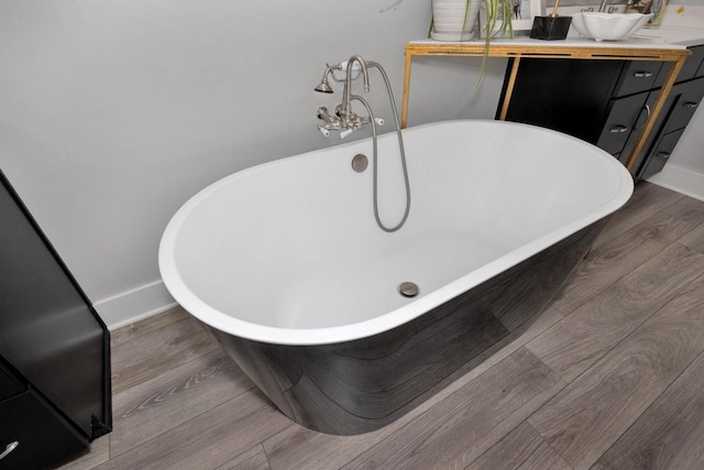 bathroom with hardwood / wood-style floors, vanity, and a tub