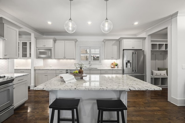 kitchen featuring backsplash, a kitchen island, stainless steel appliances, and decorative light fixtures