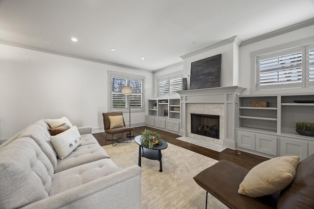 living room featuring hardwood / wood-style floors, a healthy amount of sunlight, crown molding, and a tiled fireplace