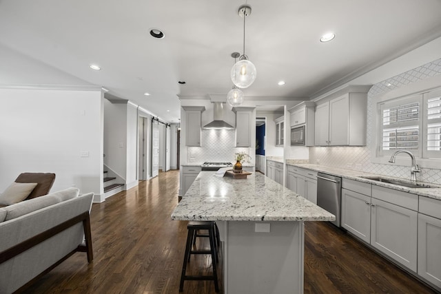 kitchen featuring a center island, sink, stainless steel appliances, wall chimney range hood, and dark hardwood / wood-style flooring