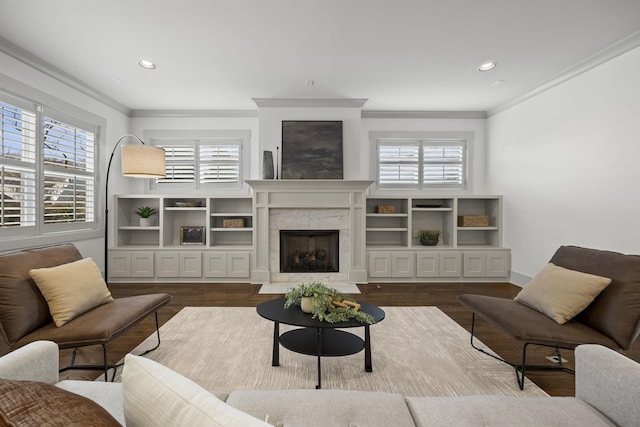 living room with a tile fireplace, wood-type flooring, and ornamental molding