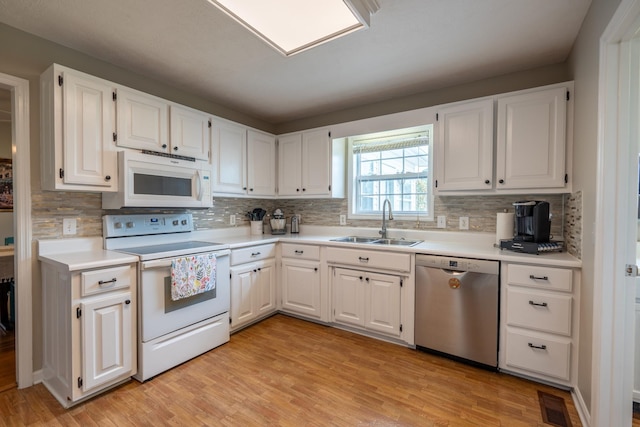 kitchen with white cabinetry, white appliances, sink, and light hardwood / wood-style flooring