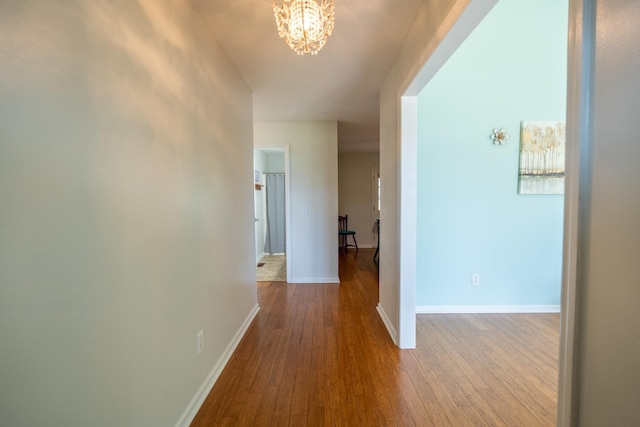 corridor with a chandelier and light hardwood / wood-style floors