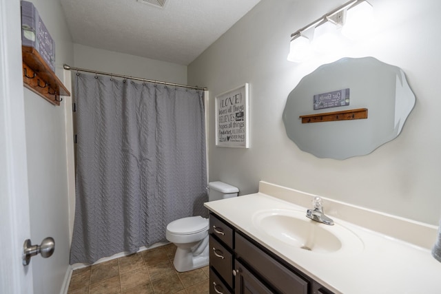 bathroom with tile patterned flooring, vanity, toilet, and a textured ceiling